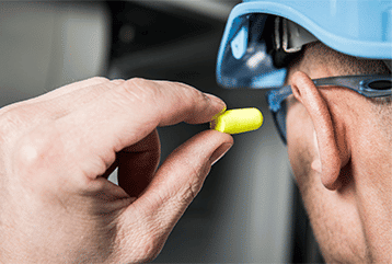 A man inserts ear plugs to protect from loud noises before entering a construction in Iowa.