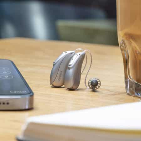 A pair of Phonak Audio Lumity hearing aids sits on a table in Iowa.